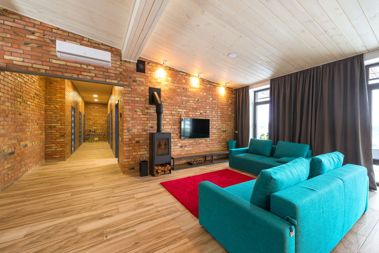 Spacious living room with blue sofas, red rug, and brick walls. Cozy and contemporary interior.